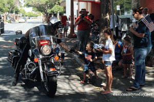 An Antioch Police Officer slaps high-five with a child during the 4th of July parade.