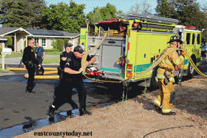Oakley Police assist firefighters with their hose.